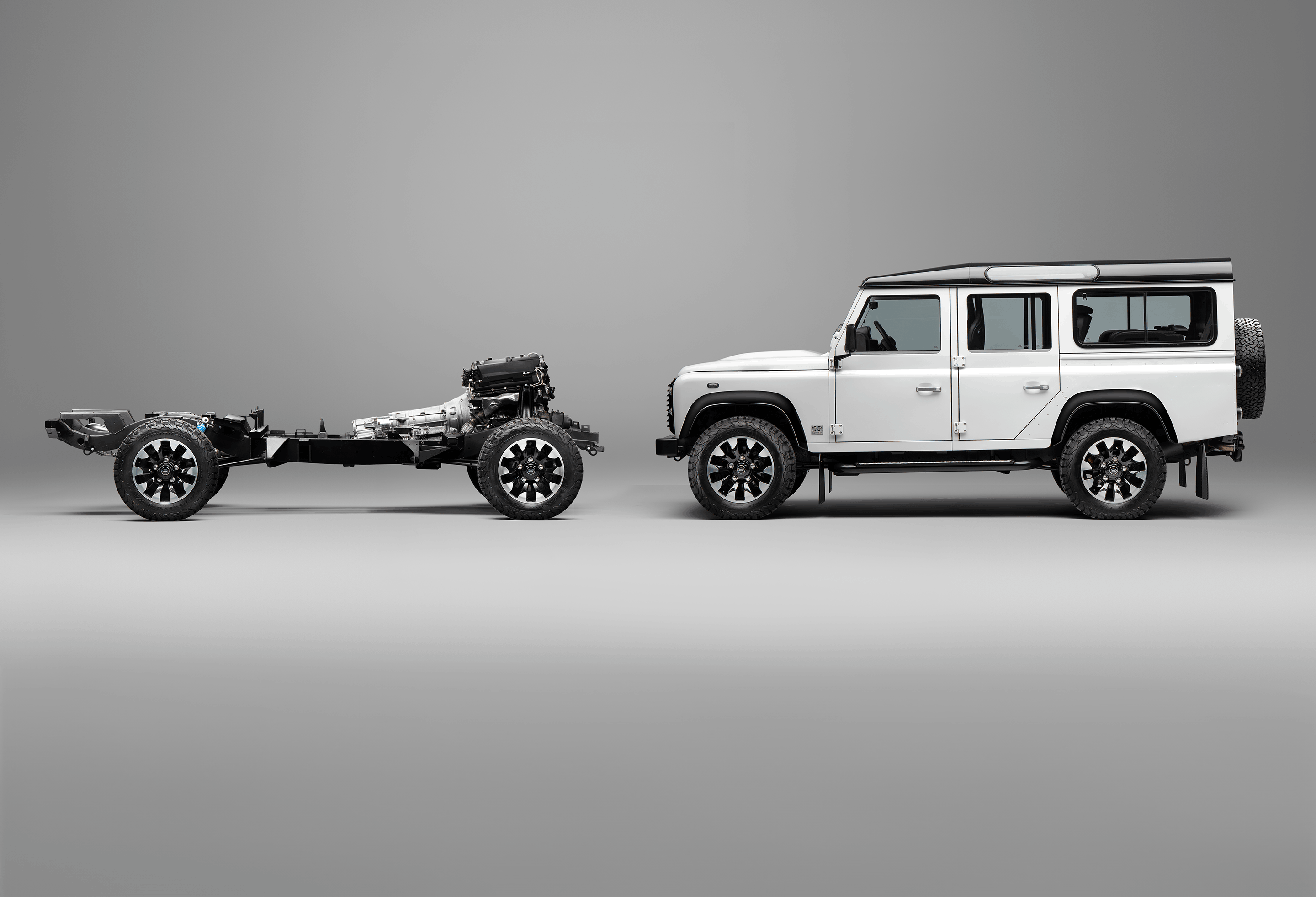 A red Defender V8 in the sand and grass.