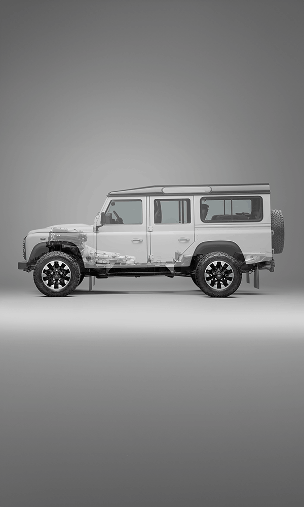 A red Defender V8 in the sand and grass.