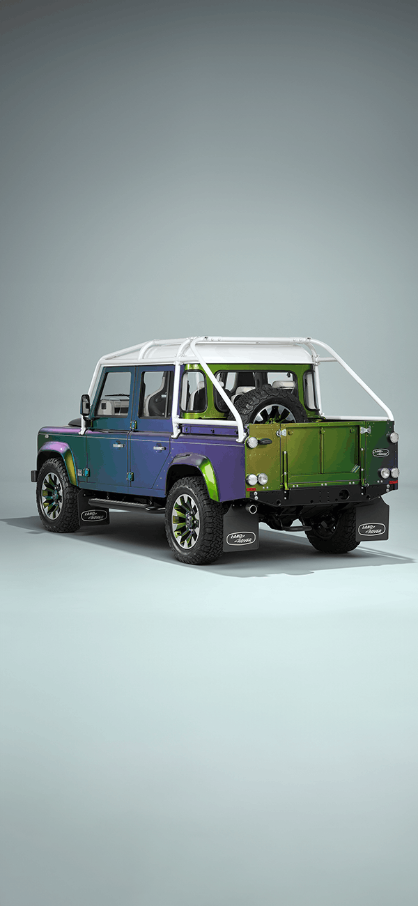 A green Defender V8 on the beach.