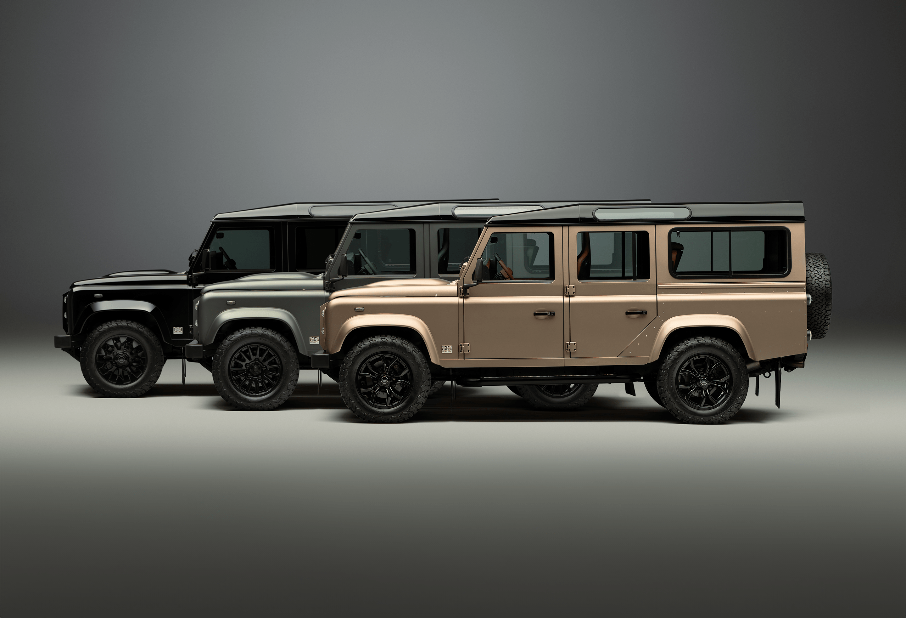 A green Defender V8 on the beach.