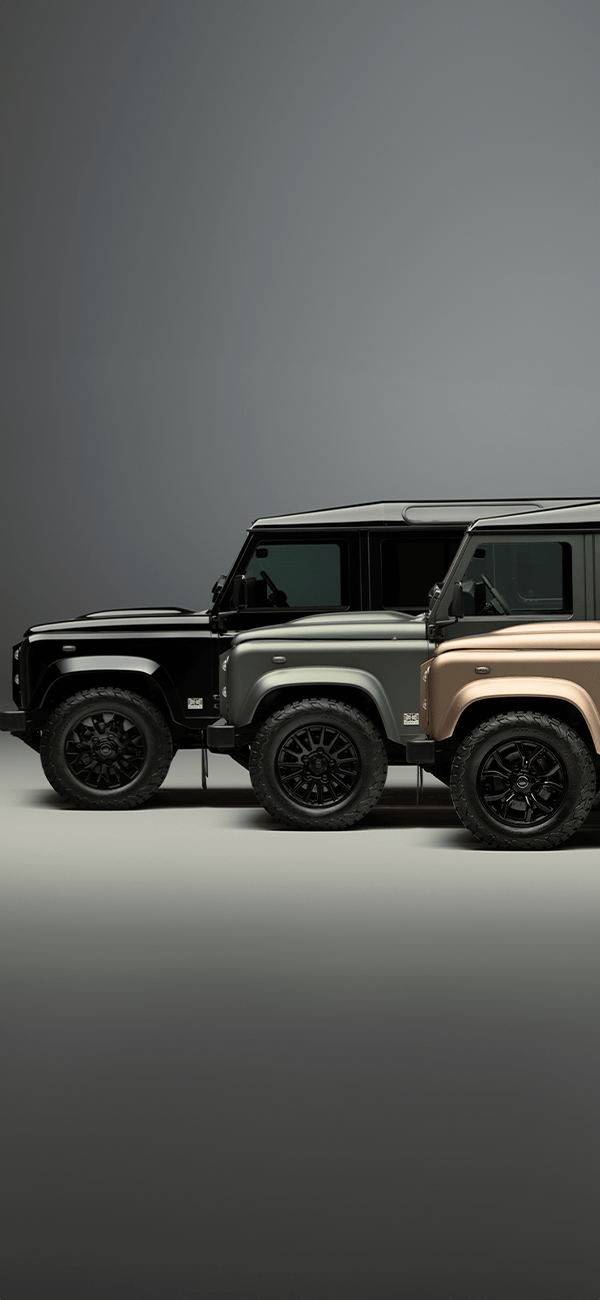 A green Defender V8 on the beach.
