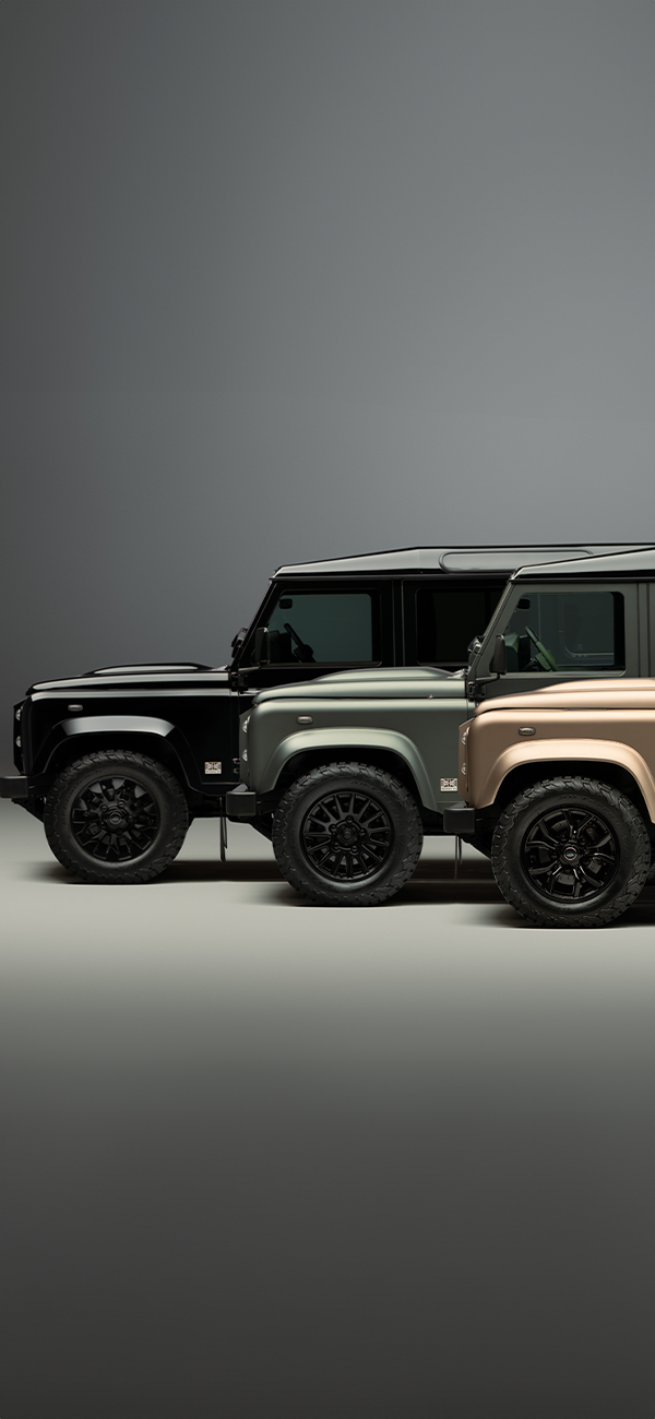 A red Defender V8 in the sand and grass.